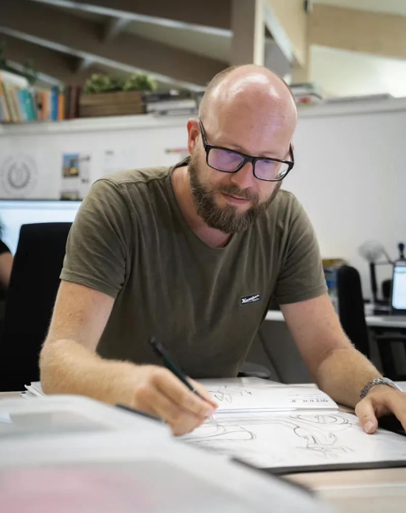 An instructional designer sketching a learning flow at a desk in a sunlit studio